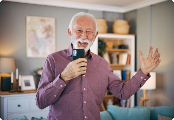 old man smiling while talking audibly into his cell phone