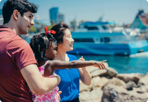 asian mom with white dad holding a black daughter pointing towards the ocean